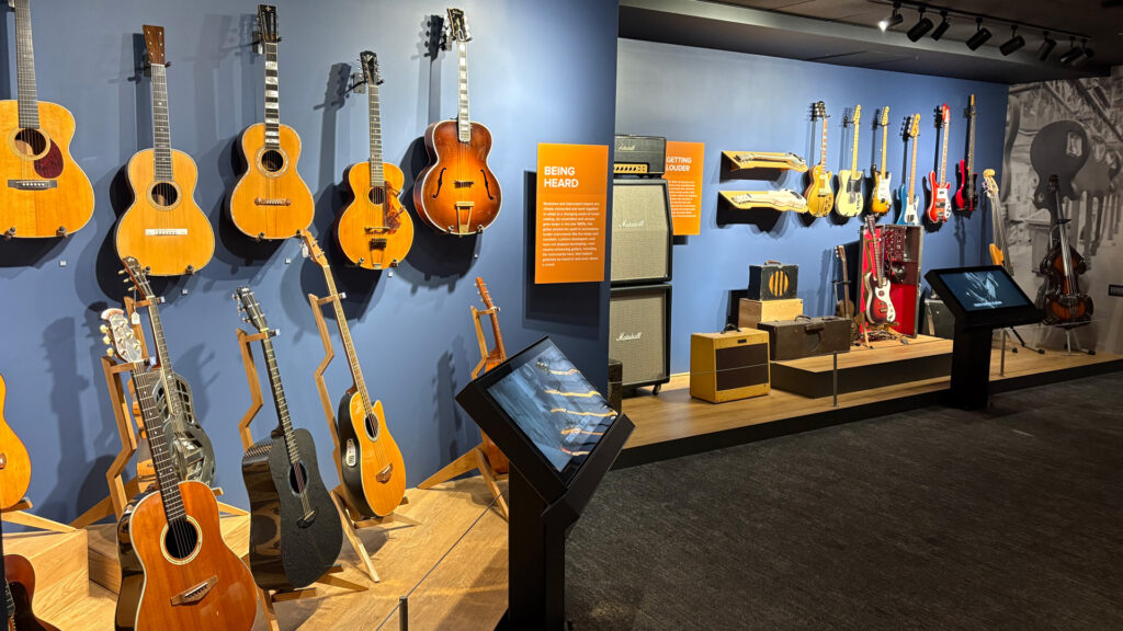 Acoustic and electric guitars mounted on a blue wall in the core galleries at the Museum of Making Music