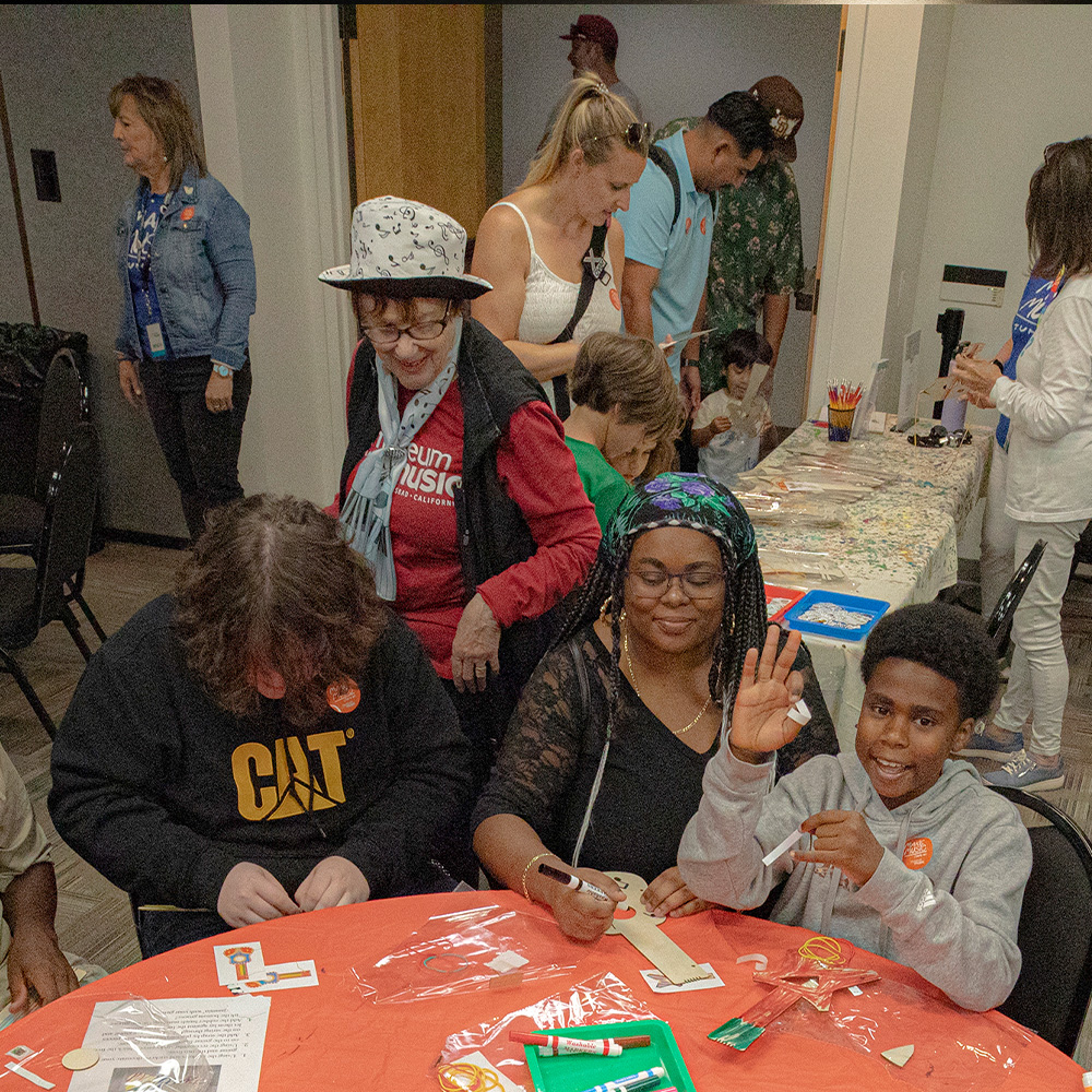 Visitors of all ages gathered around a table making crafts during a Community Day at the museum