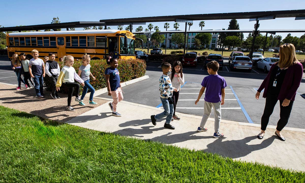 Elementary students walking from a school bus toward the museum entrance