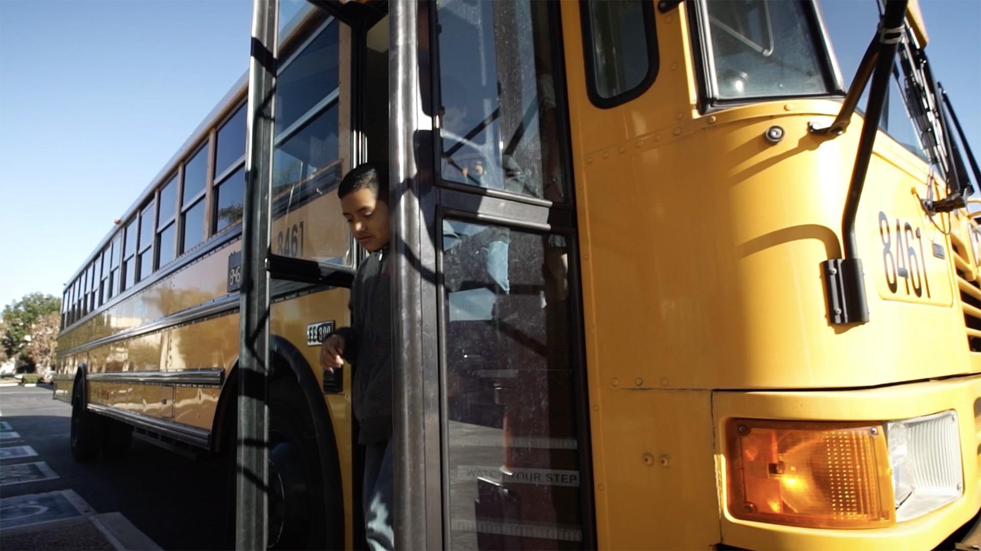 A student exiting a yellow school bus for one of the museum's field trip programs