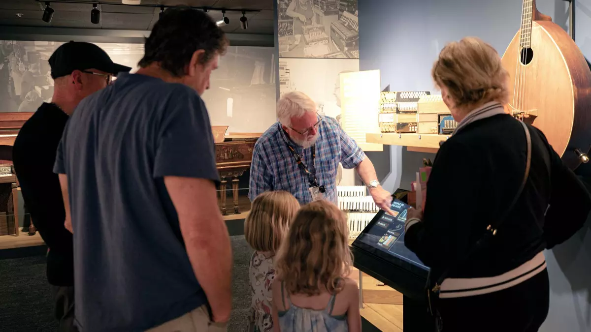 A docent showing an instrument display to a family during one of the museum's group tours.