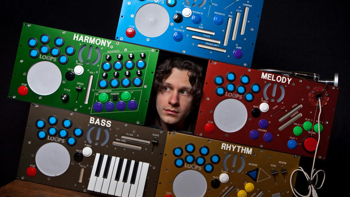 Moldover peers out between colorful custom electronic controllers labeled Harmony, Melody, Bass, and Rhythm
