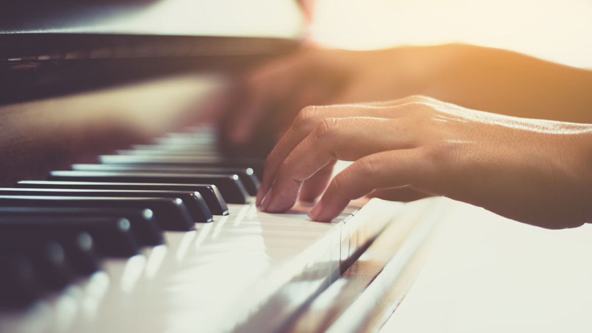 Close-up of a hand playing piano keys in warm light