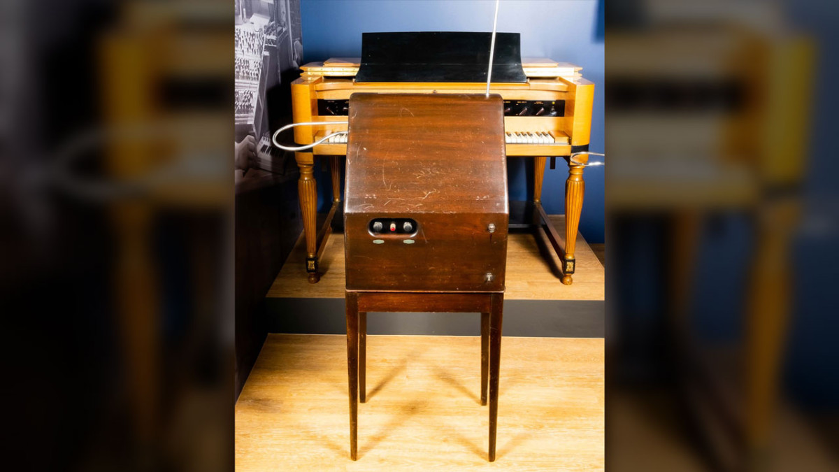 1929 RCA Theremin in a dark wood cabinet with a vertical pitch antenna, displayed in front of a vintage keyboard instrument
