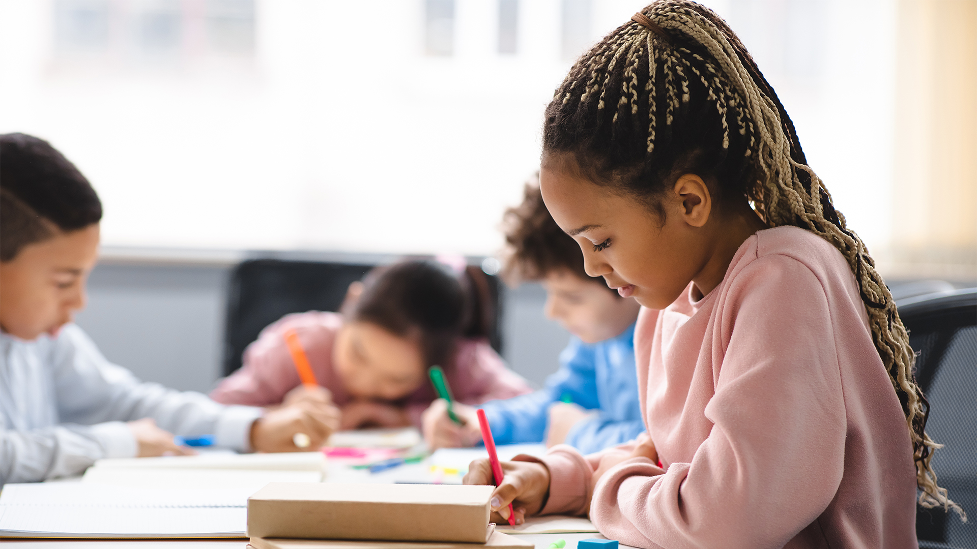 An elementary student writing at a classroom table during a music lesson