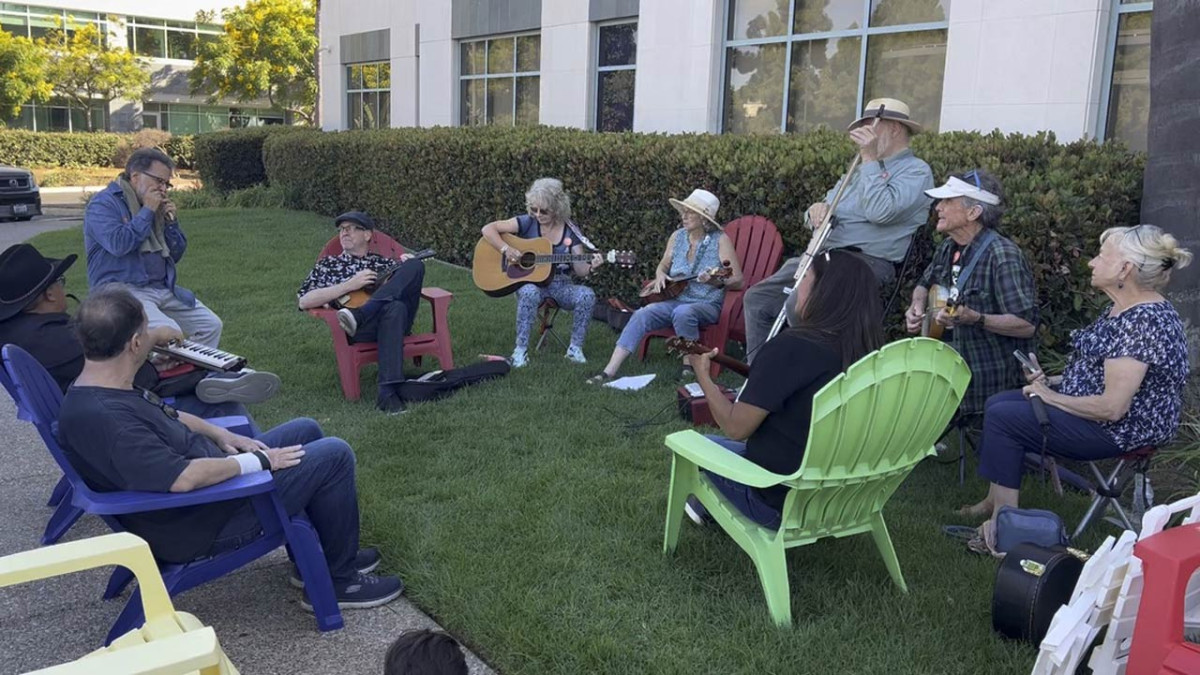 People gathered in a circle in lawn furniture outside of the Museum of Making Music, playing music together on Make Music Day 2026
