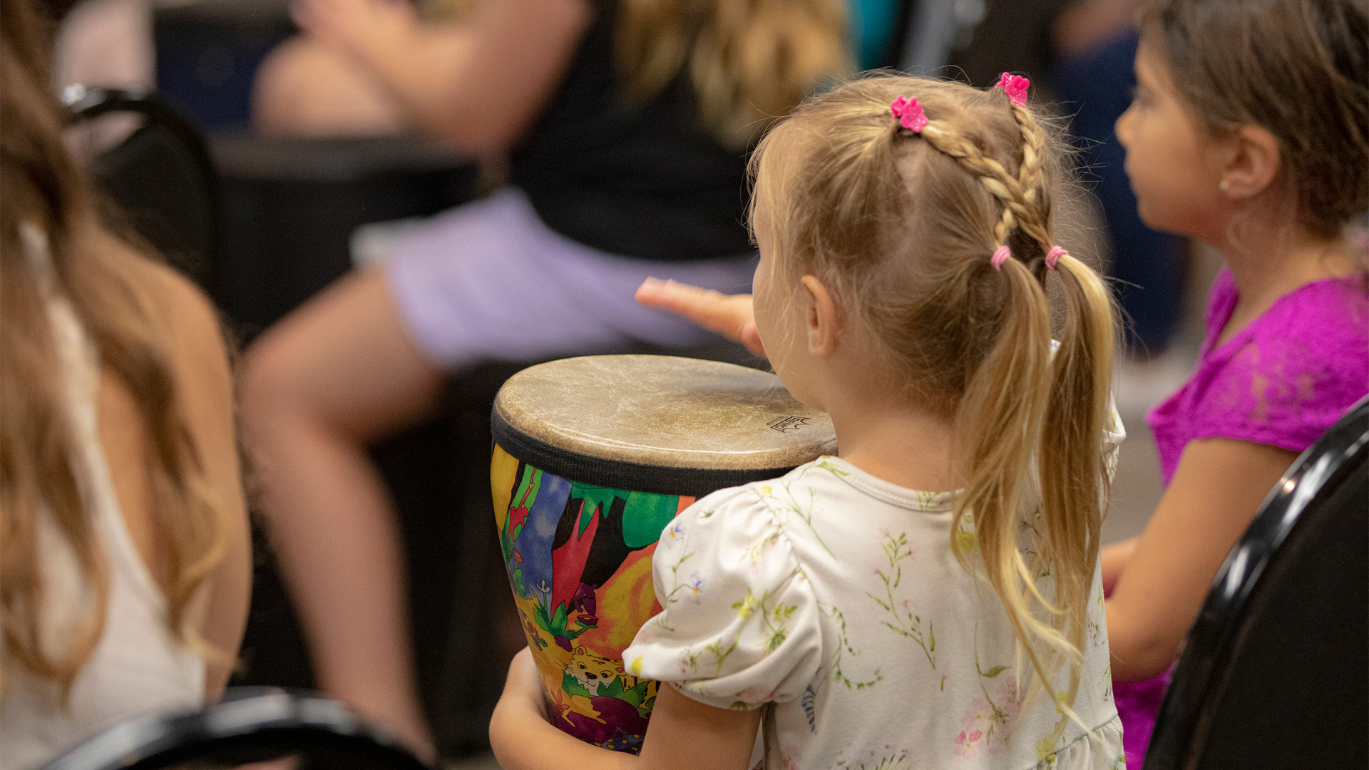 Young girl playing a djembe drum in a drum circle