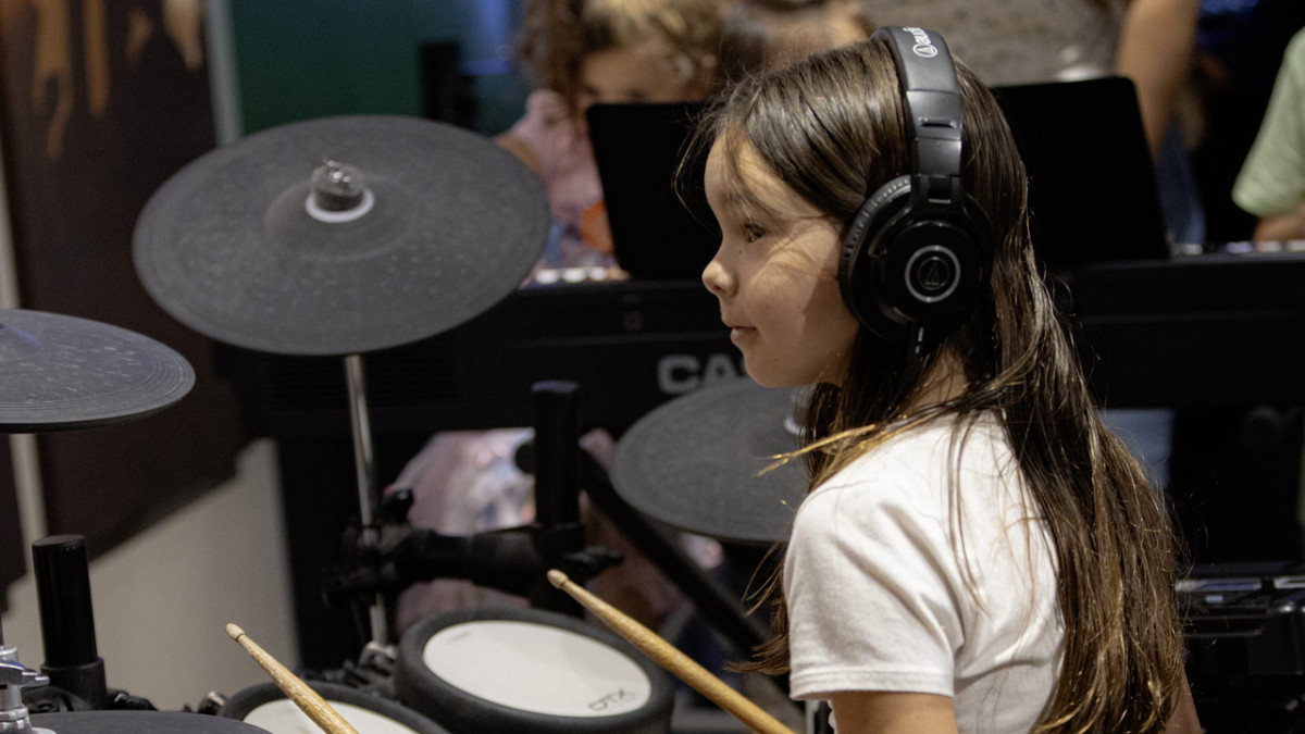 Young girl sitting at electronic drum kit