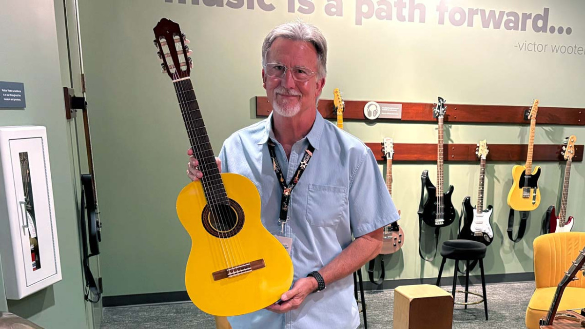 Volunteer John Denny holding a restored acoustic guitar in the museum's Sit & Play space